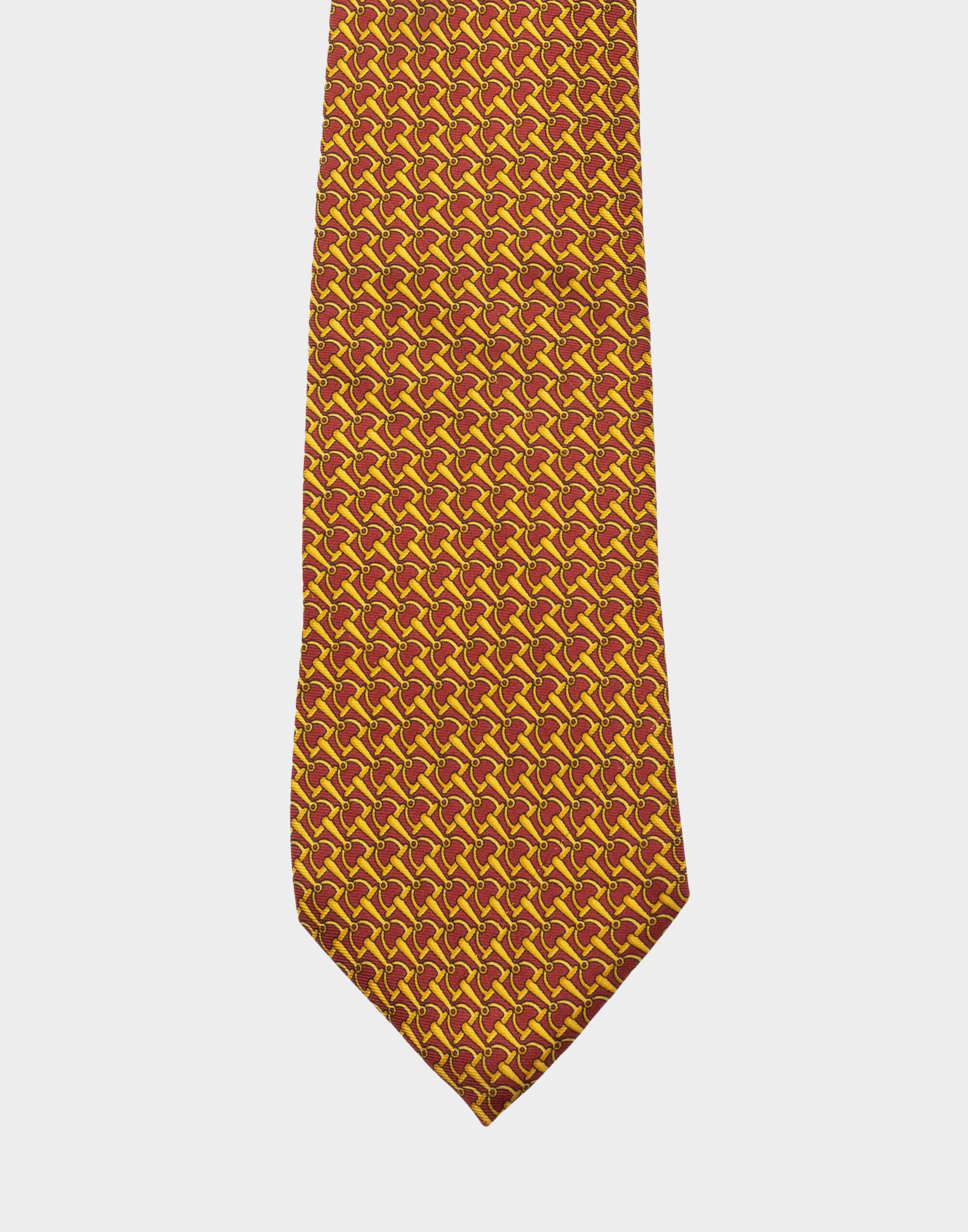 Burgundy silk tie with gold motif clips.