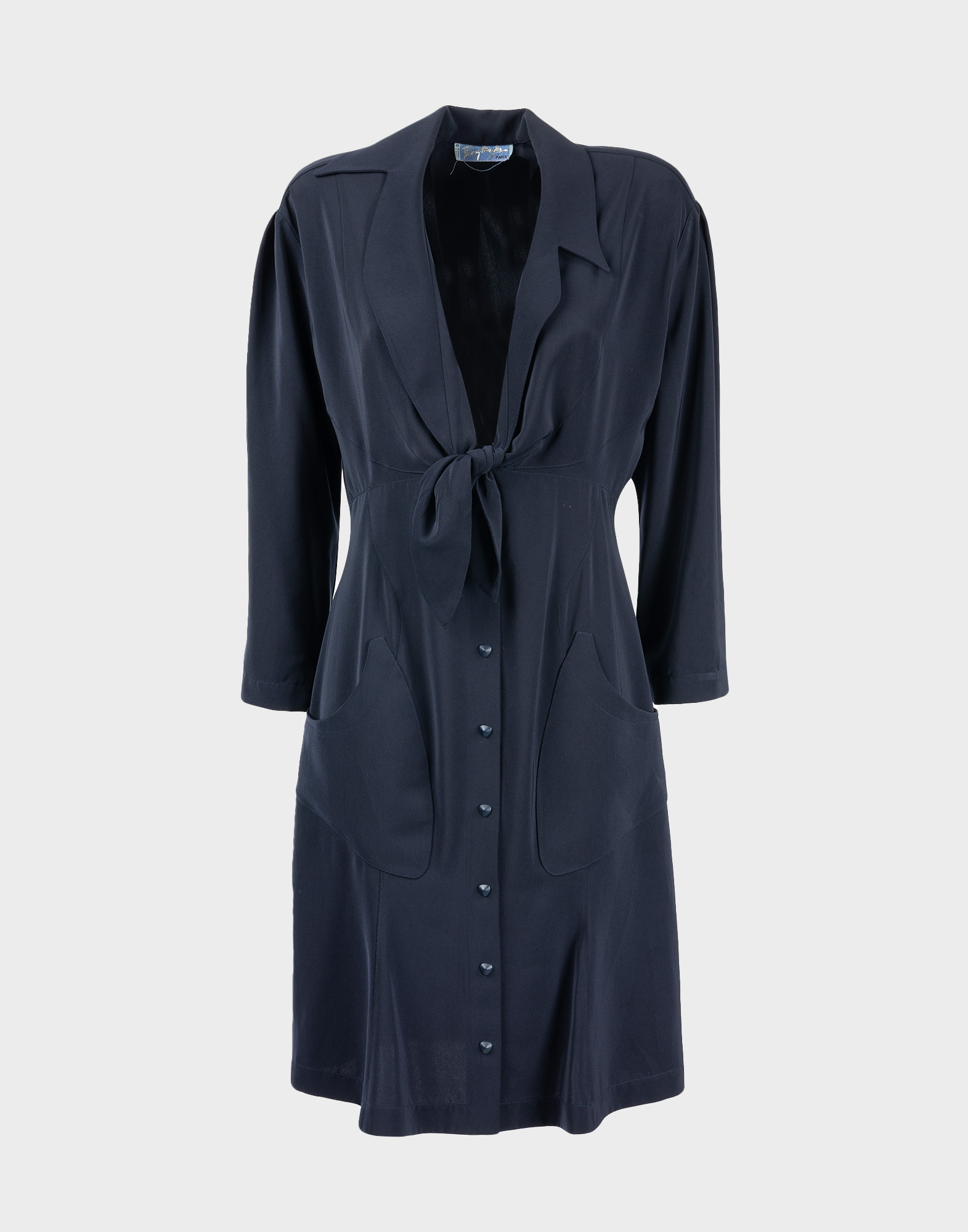 blue chemisier dress with deep V-neck, bow at the front and button fastening. Long sleeves, two pockets