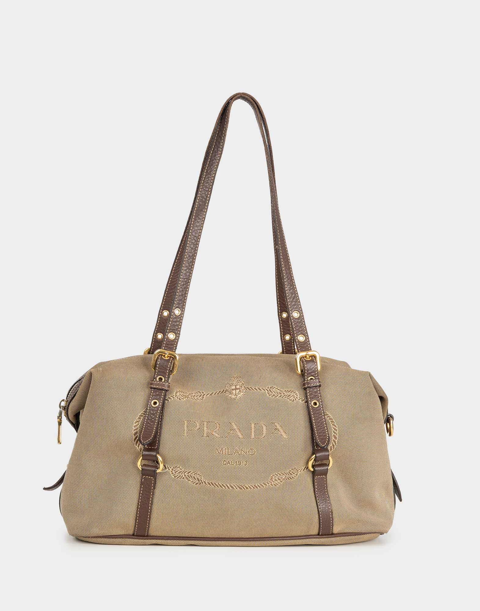 beige fabric satchel bag with embroidered logo on the front, brown leather double handle with gold details